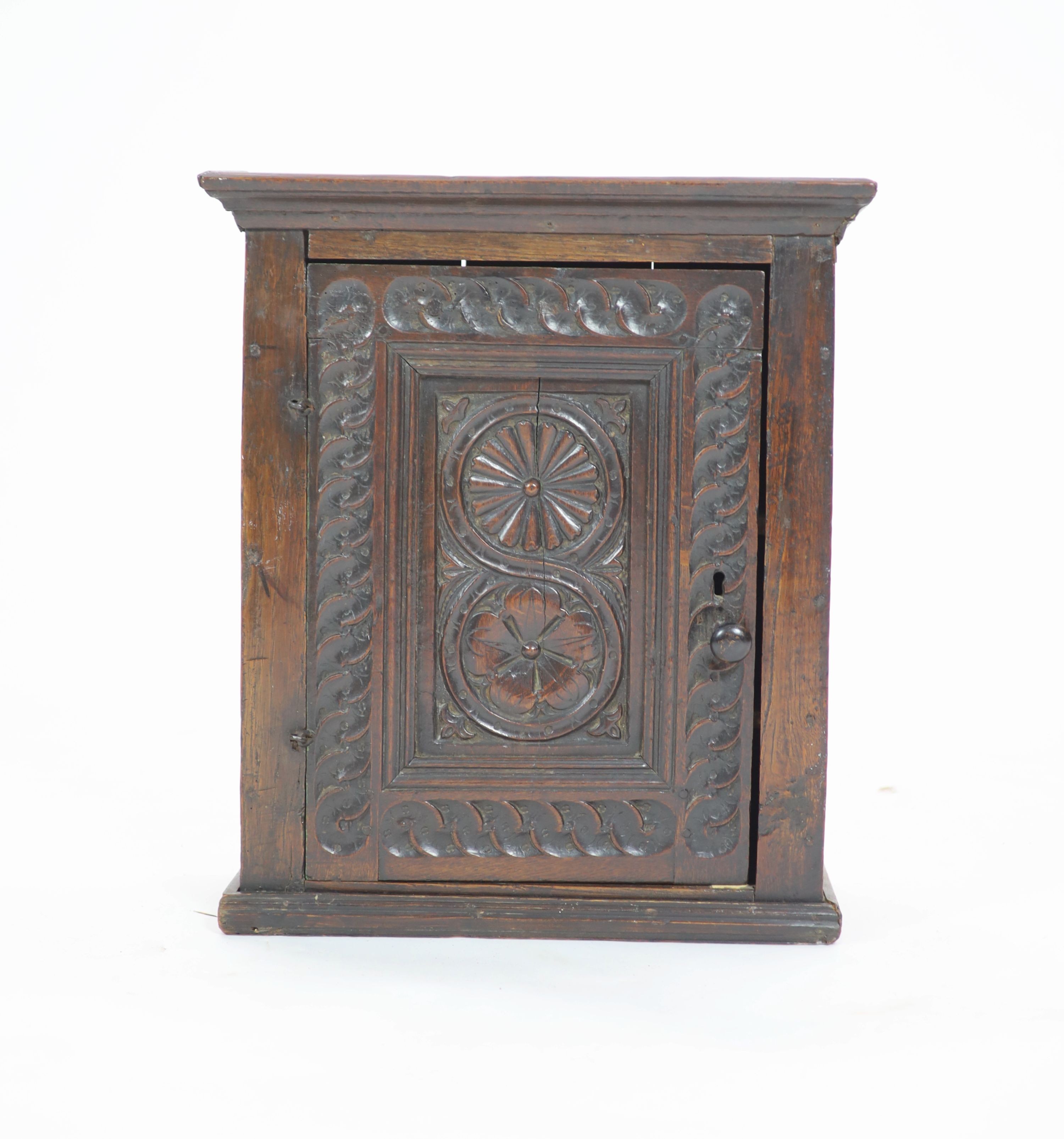 A 17th century carved oak wall cupboard, H 56cm. W 49cm. D 22cm.